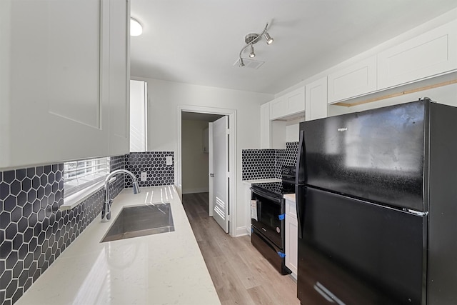 kitchen with backsplash, black appliances, sink, light wood-type flooring, and white cabinetry