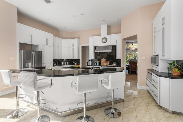 kitchen featuring range hood, white cabinetry, a breakfast bar, and stainless steel refrigerator with ice dispenser