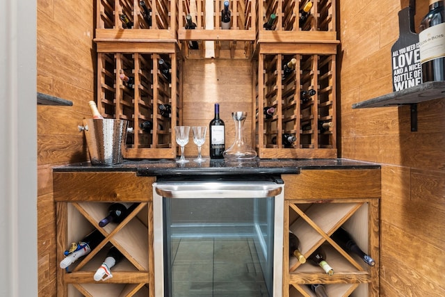 wine area featuring wine cooler and wood walls