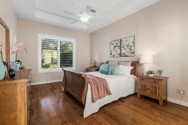 bedroom featuring dark hardwood / wood-style flooring, a tray ceiling, and ceiling fan