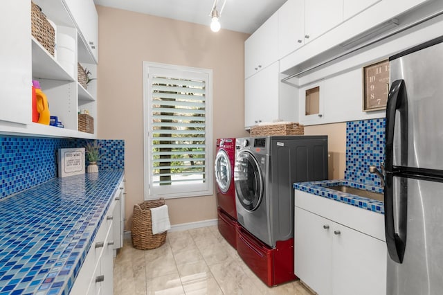 laundry area featuring washer and clothes dryer, cabinets, track lighting, sink, and light tile patterned floors