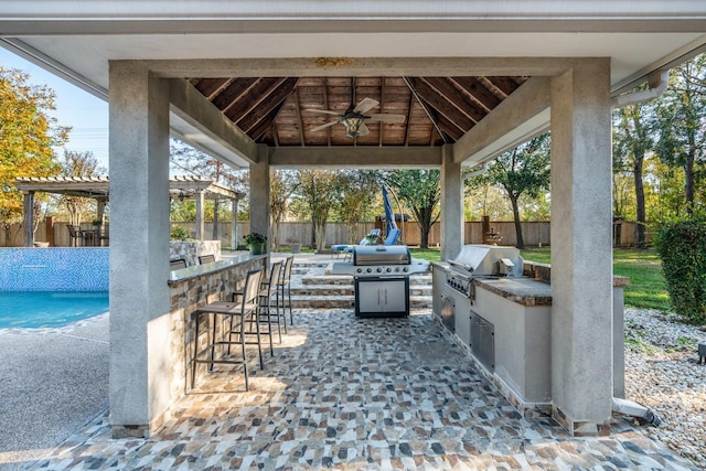 view of patio featuring an outdoor kitchen, exterior bar, ceiling fan, a gazebo, and grilling area