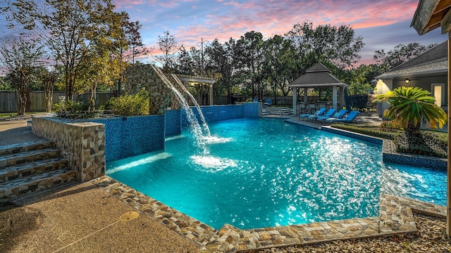 pool at dusk with a gazebo and pool water feature