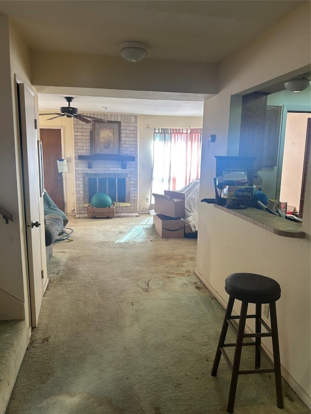 kitchen with a brick fireplace, carpet floors, ceiling fan, and a kitchen bar