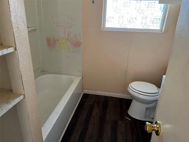 bathroom featuring hardwood / wood-style flooring, toilet, and a tub