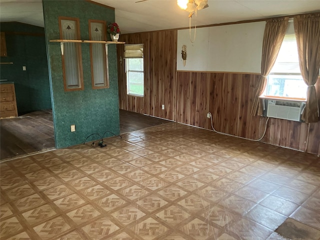 spare room with wood walls, cooling unit, and ceiling fan