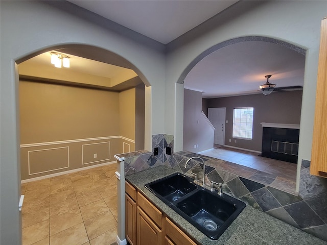 kitchen with a high end fireplace, ceiling fan, and sink