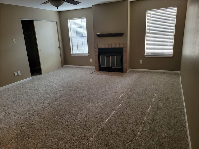 unfurnished living room with ceiling fan, light colored carpet, and a brick fireplace