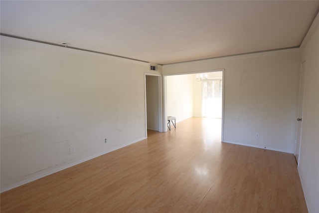 spare room with light wood-type flooring and crown molding