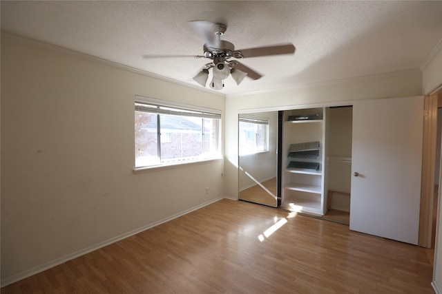 unfurnished bedroom with ceiling fan, a closet, hardwood / wood-style floors, and a textured ceiling