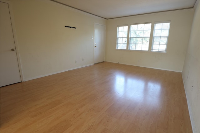 empty room with light hardwood / wood-style floors and ornamental molding