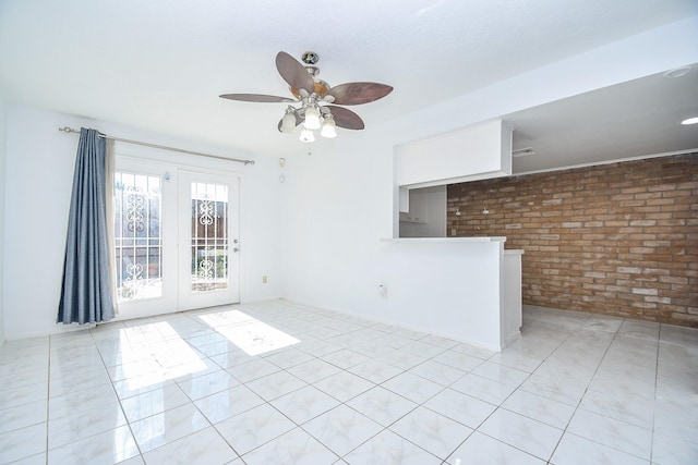 empty room with french doors, ceiling fan, and brick wall