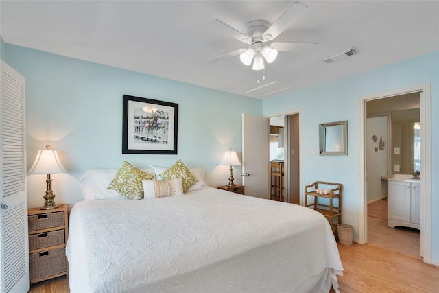 bedroom featuring light hardwood / wood-style floors, ceiling fan, and ensuite bathroom