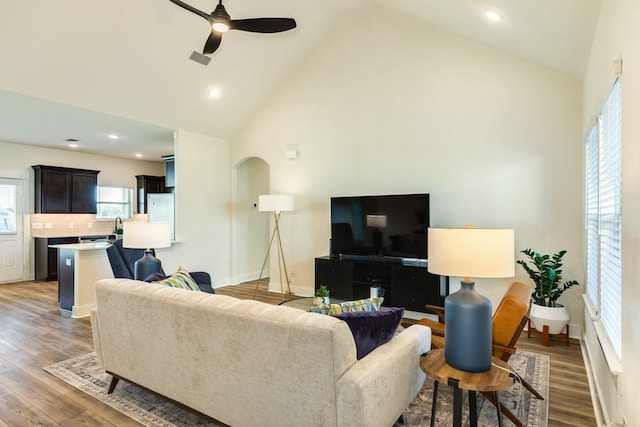 living room with hardwood / wood-style flooring, ceiling fan, and high vaulted ceiling