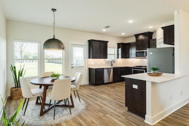 kitchen with backsplash, plenty of natural light, pendant lighting, and appliances with stainless steel finishes