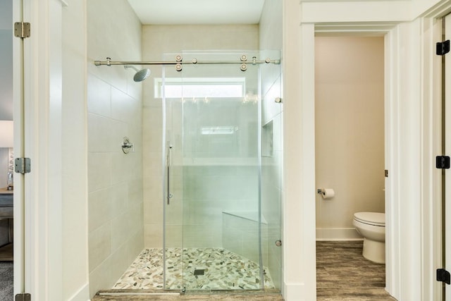 bathroom featuring hardwood / wood-style flooring, toilet, and a shower with shower door