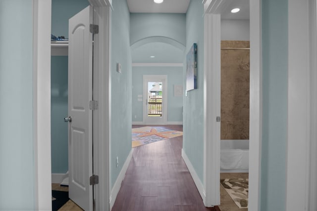 hallway with wood-type flooring and crown molding