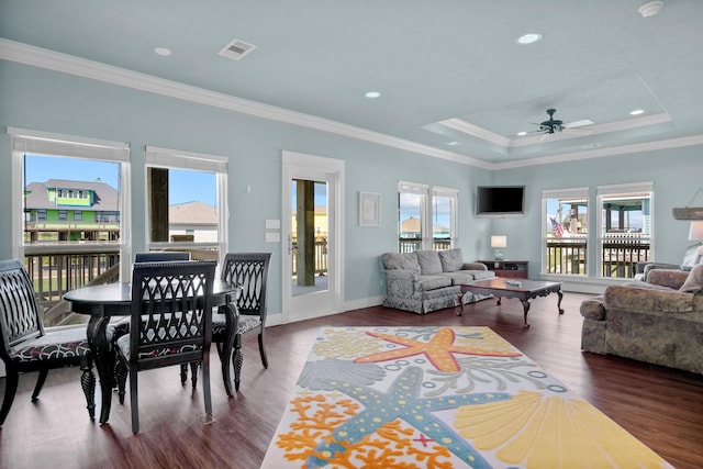 living room featuring ceiling fan, a healthy amount of sunlight, a raised ceiling, dark hardwood / wood-style floors, and crown molding