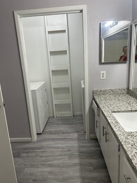 bathroom with washer and clothes dryer, vanity, and hardwood / wood-style flooring