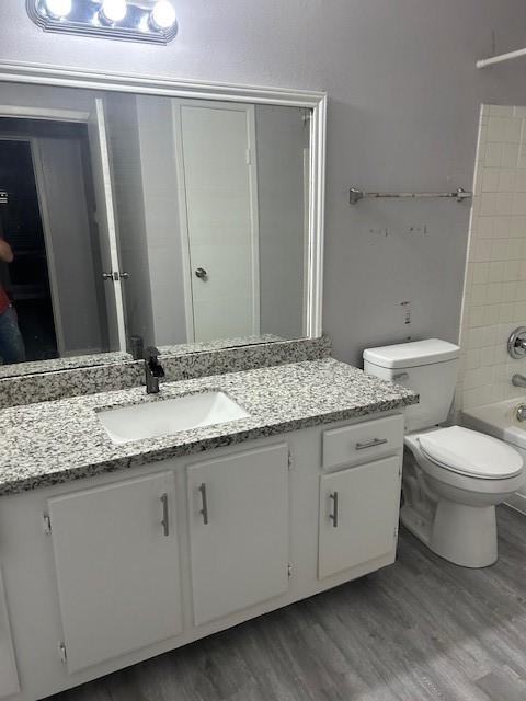 full bathroom with hardwood / wood-style flooring, vanity, toilet, and bathing tub / shower combination