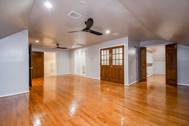 unfurnished living room featuring french doors, light hardwood / wood-style floors, ceiling fan, and lofted ceiling