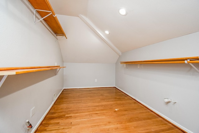 walk in closet with light hardwood / wood-style floors and lofted ceiling