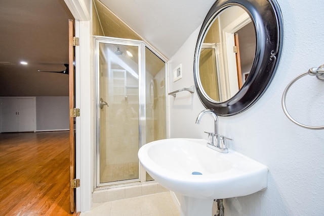 bathroom featuring tile patterned floors, walk in shower, lofted ceiling, and sink