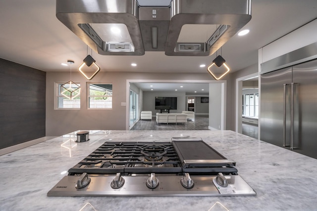 kitchen with light stone countertops, stainless steel appliances, and decorative light fixtures