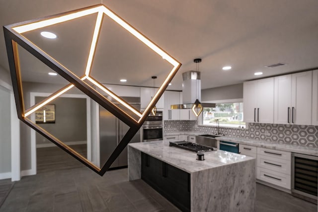 kitchen with light stone countertops, appliances with stainless steel finishes, a kitchen island, white cabinets, and wine cooler