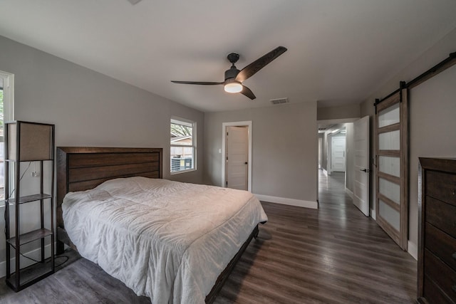 bedroom featuring a barn door, ceiling fan, and dark wood-type flooring