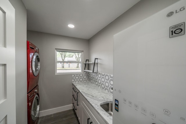 laundry room featuring cabinets, dark wood-type flooring, sink, water heater, and stacked washer / drying machine