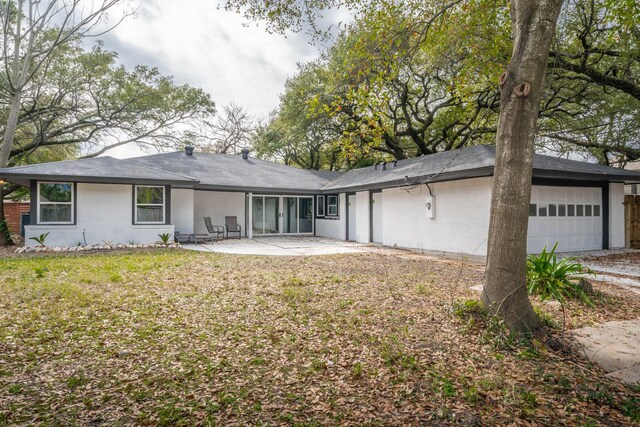 back of property with a garage and a patio area