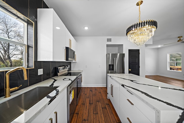 kitchen featuring pendant lighting, sink, a notable chandelier, white cabinetry, and stainless steel appliances