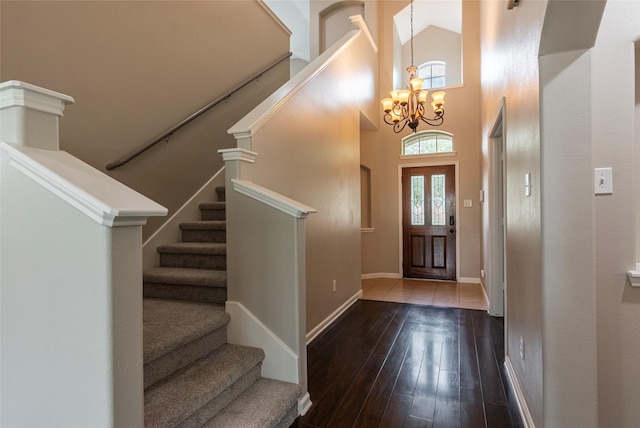 foyer entrance featuring dark wood-type flooring, a high ceiling, and a notable chandelier