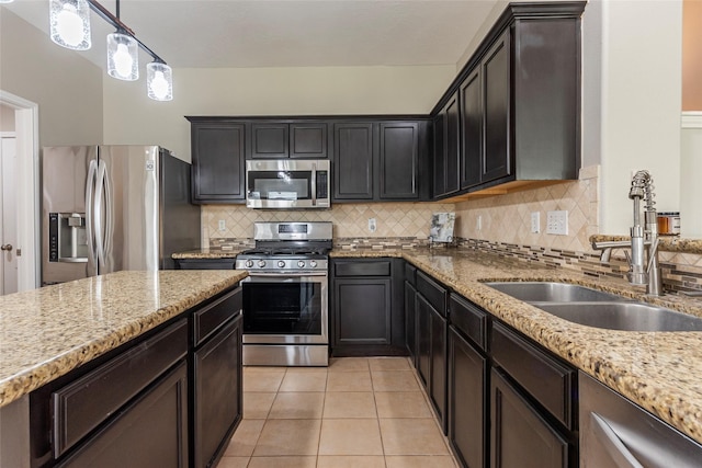 kitchen with appliances with stainless steel finishes, tasteful backsplash, sink, light tile patterned floors, and hanging light fixtures