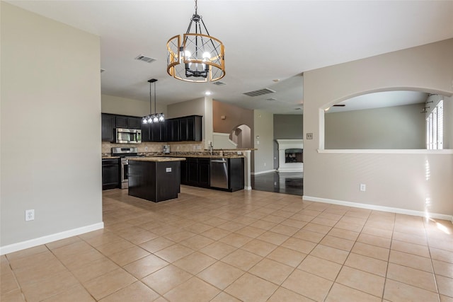 kitchen with a center island, an inviting chandelier, appliances with stainless steel finishes, decorative light fixtures, and light tile patterned flooring