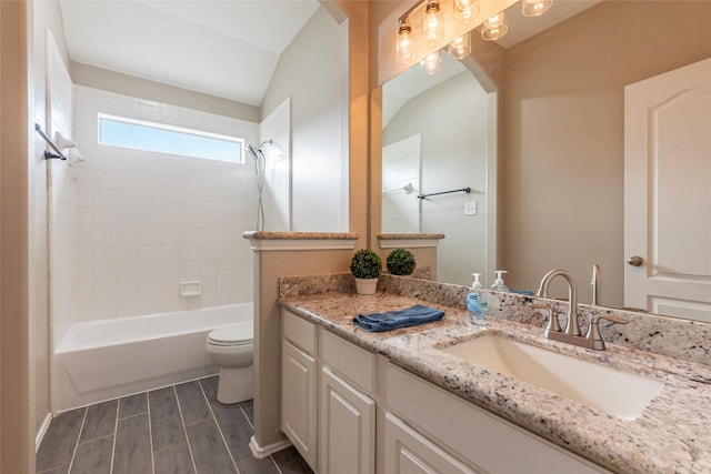 full bathroom with toilet, vanity, lofted ceiling, and washtub / shower combination