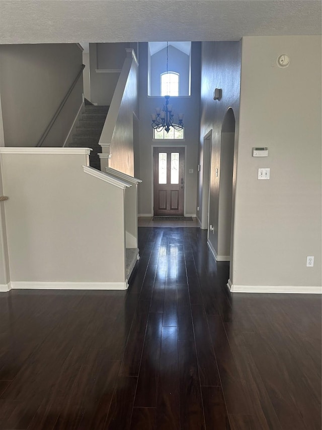 entrance foyer featuring a high ceiling, a textured ceiling, dark hardwood / wood-style floors, and an inviting chandelier