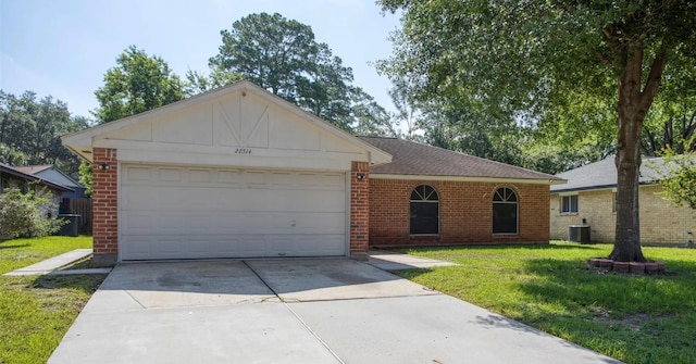 ranch-style house with central AC unit, a garage, and a front yard