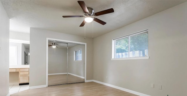 unfurnished bedroom with ceiling fan, light hardwood / wood-style flooring, a textured ceiling, a closet, and built in desk