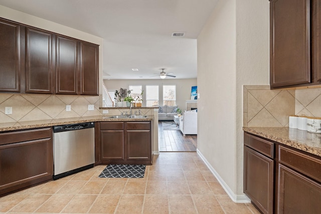 kitchen featuring dishwasher, sink, decorative backsplash, dark brown cabinets, and light stone counters