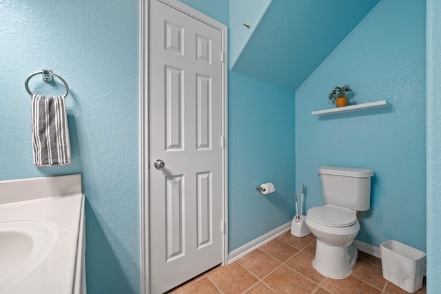 bathroom featuring sink, tile patterned flooring, vaulted ceiling, and toilet