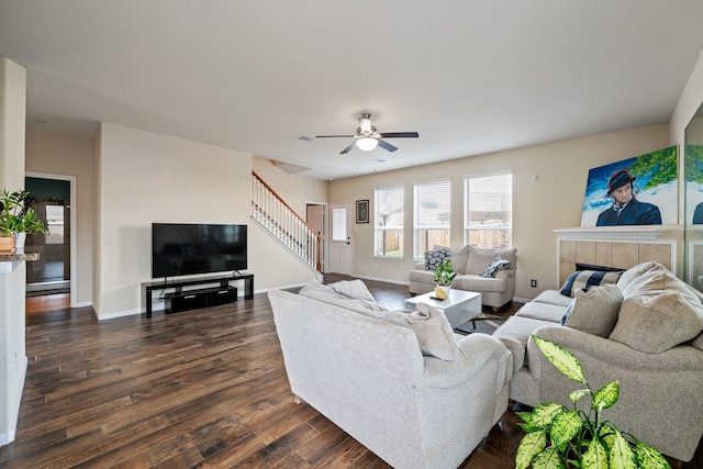 living room with dark hardwood / wood-style floors, ceiling fan, and a tiled fireplace