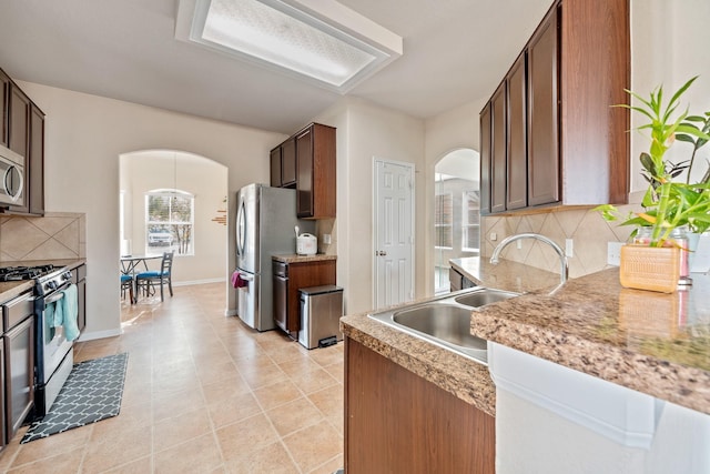 kitchen with light tile patterned floors, stainless steel appliances, tasteful backsplash, and sink