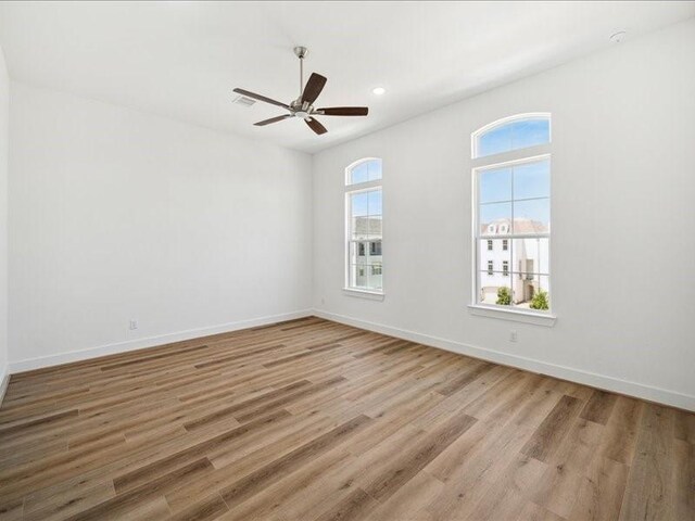 empty room with ceiling fan and light hardwood / wood-style flooring