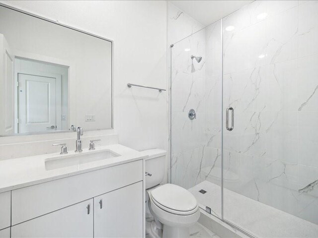 bathroom featuring vanity, toilet, and a shower with shower door