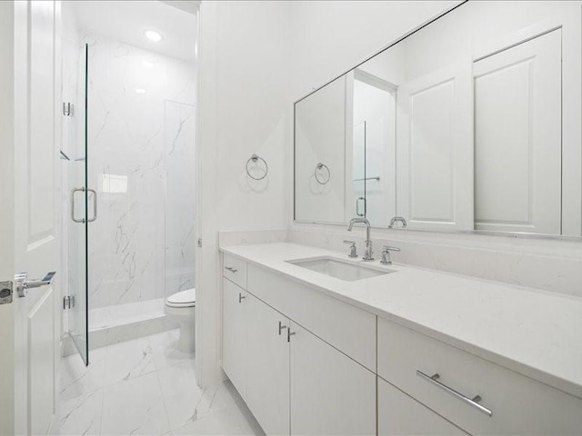 bathroom featuring vanity, toilet, and a shower with shower door