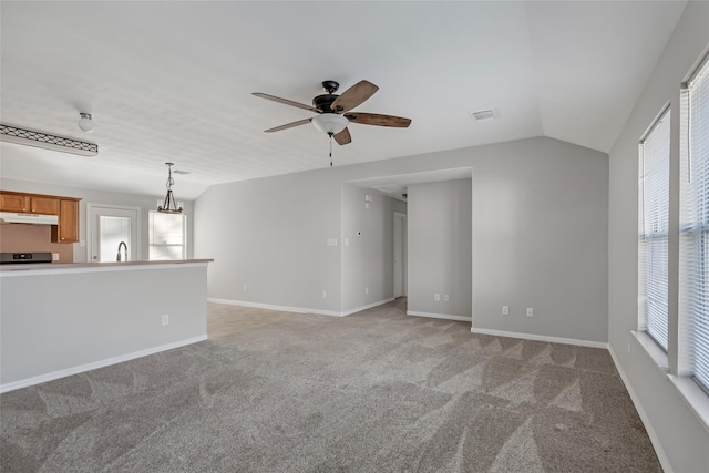 unfurnished living room featuring ceiling fan, sink, light colored carpet, and vaulted ceiling