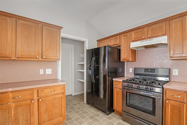 kitchen featuring vaulted ceiling, backsplash, black fridge, and stainless steel gas range