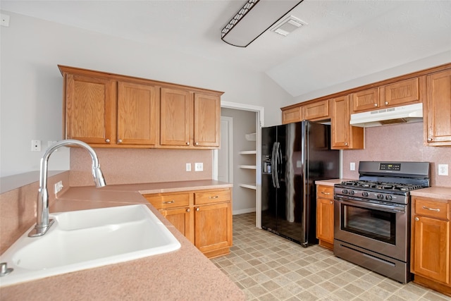 kitchen with black fridge, sink, lofted ceiling, and stainless steel range with gas stovetop